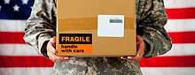 A US Army solder holding a package that says "Fragile" on the exterior.